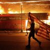 'Черная война' в США: худшее еще впереди (Протестующий несет перевернутый американский флаг возле горящего здания в Миннеаполисе | © AP Photo …) Протестующий несет п…